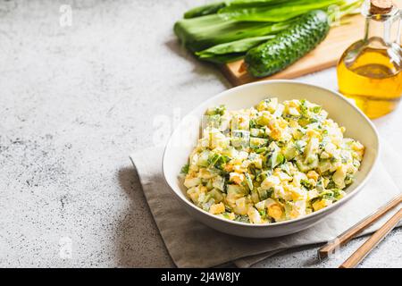 Salade saine de poireaux sauvages verts, œuf poché et concombre, gros plan. Salade d'ail sauvage avec œufs durs. Banque D'Images