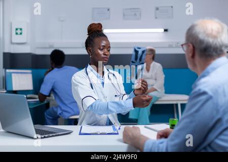 Spécialiste en radiologie d'un établissement de santé afro-américain qui examine les images radiographiques et analyse les résultats d'imagerie. Expert en radiologie examinant une image d'acquisition radiographique et concluant un diagnostic basé sur les résultats Banque D'Images