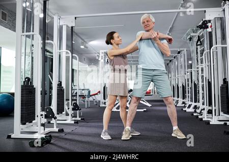 Portrait complet de la femme thérapeute aidant le patient senior à faire des exercices dans la clinique de réadaptation, espace de copie Banque D'Images