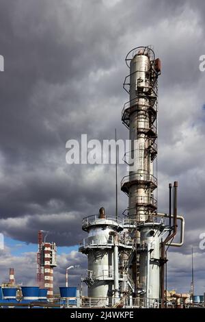 Anciennes tours de colonnes et réacteurs de distillation rectificative à la raffinerie de méthanol sous ciel orageux avec fond de nuages sombres dans l'entreprise de l'usine chimique Banque D'Images