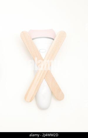 Épilation à la cire, concept d'épilation. Pose à plat de l'épilateur blanc avec des bâtonnets en bois sur fond blanc Banque D'Images