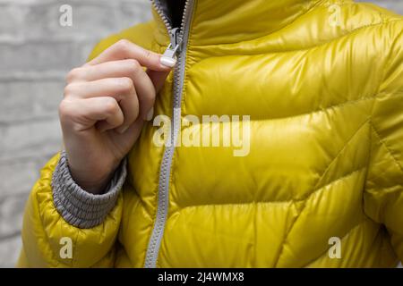 une femme zippe sa veste autour de sa gorge. Photo de haute qualité Banque D'Images