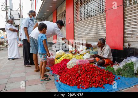 Homme assis sur le trottoir vendant au poids des fleurs à Trichy, Tamil Nadu, Inde Banque D'Images