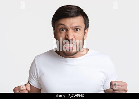 Furious Man Clenching Fists in rage on White Studio Background Banque D'Images