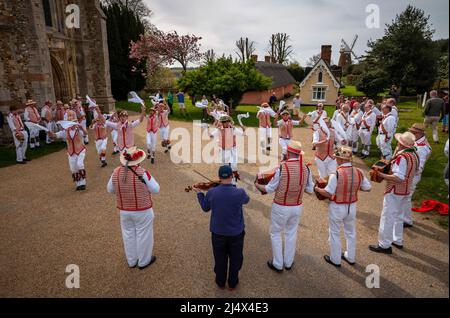 Lundi de Pâques Morris Dancing Thaxted Essex, Royaume-Uni. 18th avril 2022. À la fin du printemps, par temps chaud, les danseuses de Morris Thaxted en rouge et blanc, en visitant les danseurs de Dyke Morris en marron et en blanc du sud du Cambridgshire, effectuent des danses traditionnelles de dMorris dans le triage de l'église de Thaxted avec les maisons d'alms Thaxted et le moulin de John Webb en arrière-plan. Crédit : BRIAN HARRIS/Alay Live News Banque D'Images