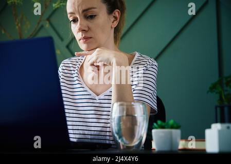 Femme caucasienne assise à une table au bureau à domicile et travaille avec un ordinateur portable. Travailleur indépendant à distance Banque D'Images