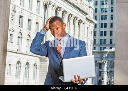 Homme d'affaires qui réfléchit dur. Robe de chambre bleue, cravate à motifs, jeune homme noir debout devant un immeuble de bureau de style vintage, fronces, ha Banque D'Images