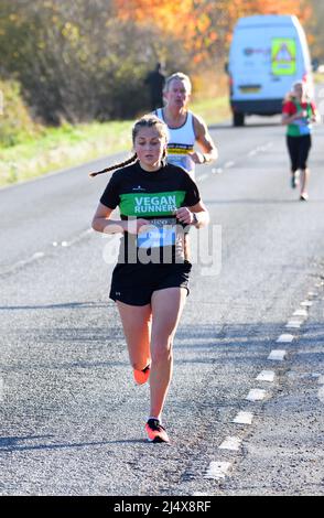 Jeune femme sur la route dans le semi-marathon de St Neots Banque D'Images