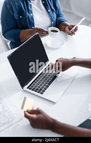 vue rognée d'un homme afro-américain qui détient une carte de crédit et qui pointe vers un ordinateur portable Banque D'Images