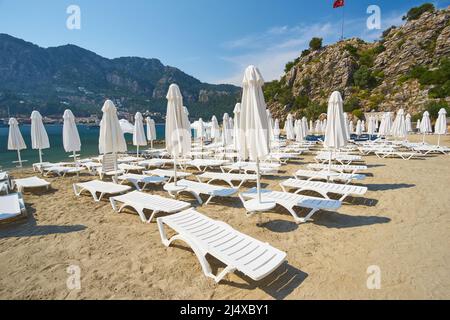 plage en mer par temps sans nuages. Nombreux transats blancs et parasols compliqués Banque D'Images