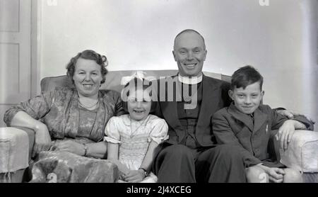 1950s, historique, assis ensemble sur le canapé pour une bonne photo de famille, un vicaire anglais du village d'Oxford avec sa femme et deux jeunes enfants, Angleterre, Royaume-Uni. Banque D'Images