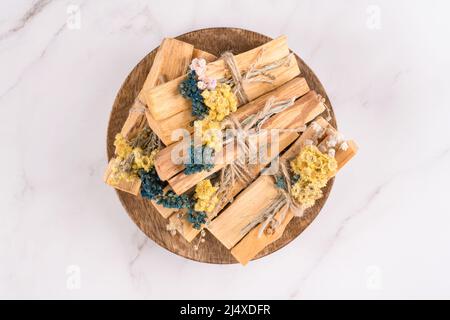 Vue de dessus sur les bâtons de bois Saint pour la méditation et les pratiques spirituelles sur fond de table en marbre blanc. Palo santo se colle aux bouquets de fleurs séchées Banque D'Images