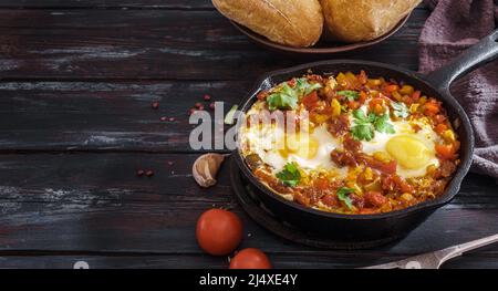 Œufs frits sur une casserole avec petits pains et espace de copie. Shakshouka est un plat maghrébine d'œufs pochés dans une sauce de tomates, d'huile d'olive, de poivrons, d'oignons et d'ail Banque D'Images