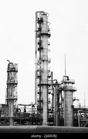 Anciennes tours de colonnes et réacteurs de raffinage de distillation de méthanol sous ciel gris dans une usine chimique. Noir et blanc industriel BW Banque D'Images