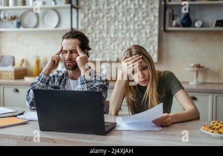 Triste choqué millénaire mari caucasien avec le chaume et la femme payer des factures, des impôts et ont des problèmes avec ordinateur portable Banque D'Images