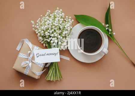 Bouquet de fleurs de Lily de la vallée, cadeau et tasse de café sur fond beige. Banque D'Images