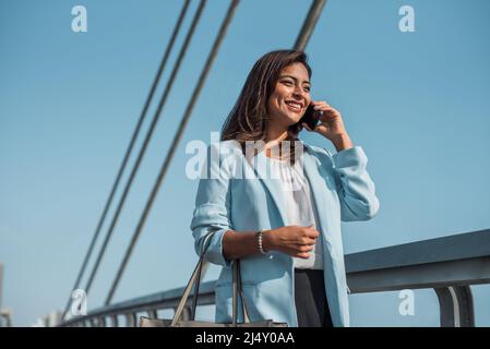 Belle femme d'affaires hispanique utilise et parle au téléphone à l'étranger. Banque D'Images