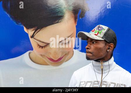 Un homme pincé portant une casquette à visière se dresse devant une photo géante d'une jeune femme souriant. Bruxelles. Banque D'Images