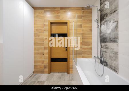 Porte-douche et baignoire blanche à l'intérieur de la salle de bains Banque D'Images