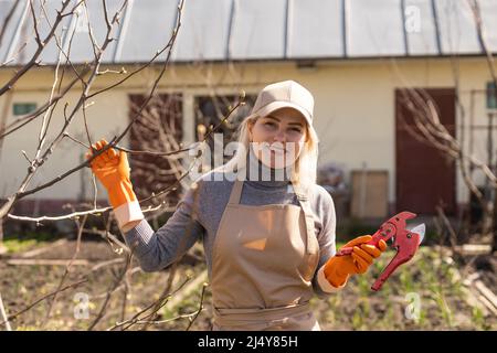 Jeune femme prenant soin du jardin. Branche de l'arbre de coupe. Banque D'Images