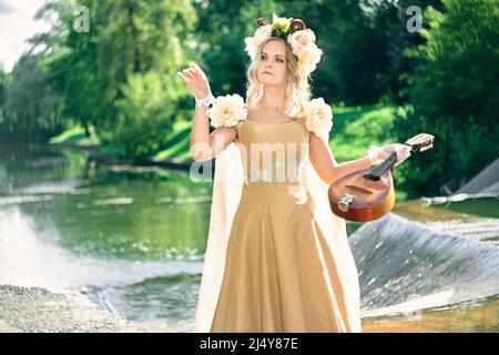 femme en robe joue une femme en robe joue une petite guitare près de la cascade. concept inspiration Banque D'Images