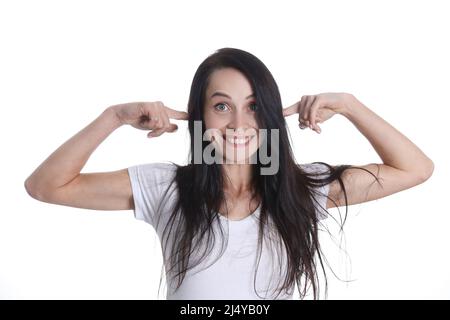 Portrait de femme souriante met les doigts dans les oreilles Banque D'Images