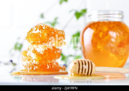 Abeille et nid d'abeille avec un balancier de miel sur fond de marbre blanc. Banque D'Images