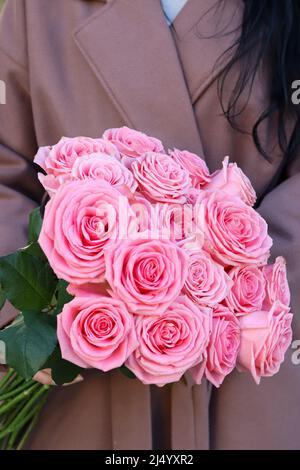 Beau bouquet de roses roses. Femme en manteau brun tenant bouquet de roses. Banque D'Images