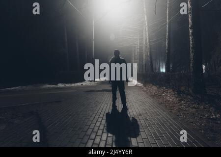 Triste homme seul marchant le long de la ruelle dans le parc de nuit. Banque D'Images