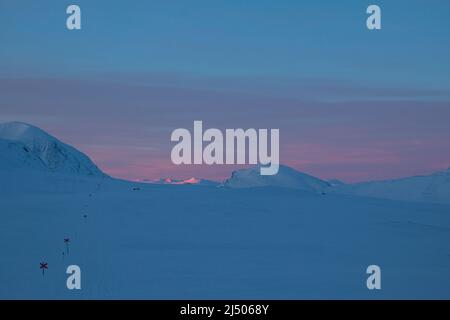 Sentier de randonnée de Kungsleden recouvert de neige au lever du soleil pendant la saison hivernale, une étendue entre les refuges de montagne de Salka et de Singi, Laponie, Suède Banque D'Images