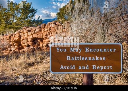 Avertissement de Rattlesnake signe près des ruines du mur défensif du site ancestral de Pueblo au parc historique national de Pecos au Nouveau-Mexique. Banque D'Images