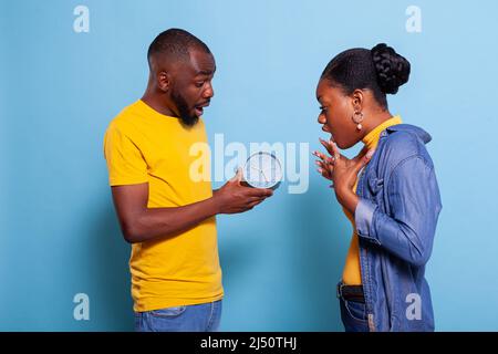 Des personnes anxieux qui vérifient l'horloge et qui se tiennent tard au travail, regardent l'heure sur la montre. Homme et femme impatients d'être en état de choc après la date limite de passage en studio. Couple après l'heure et les minutes Banque D'Images