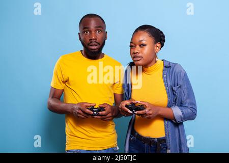 Petit ami et petite amie jouant à des jeux vidéo avec la manette sur la console. Couple moderne tenant le joystick pour jouer en ligne ensemble, en utilisant des accessoires à Amuse-toi bien. Activités de loisirs Banque D'Images