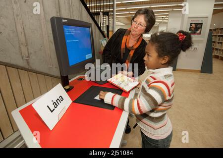 La petite fille obtient de l'aide en empruntant un livre de la bibliothèque. Banque D'Images