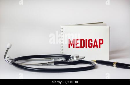 Medigap mot sur le bloc-notes, stéthoscope et fond blanc Banque D'Images