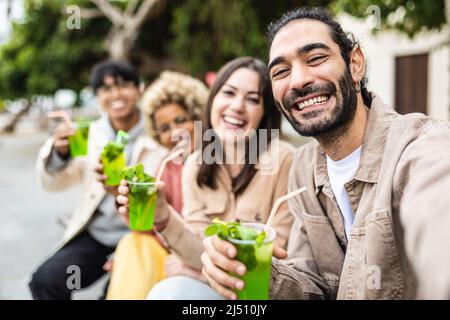 Des amis multiraciaux heureux qui boivent des cocktails dans la rue de la ville Banque D'Images