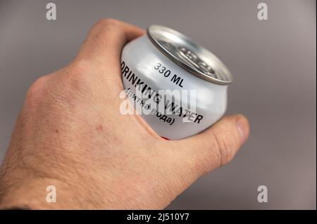 Un homme tient une bonde d'eau potable dans sa main sur un fond gris. De l'eau fraîche dans la CAN. Aide humanitaire aux Ukrainiens pendant la guerre Banque D'Images