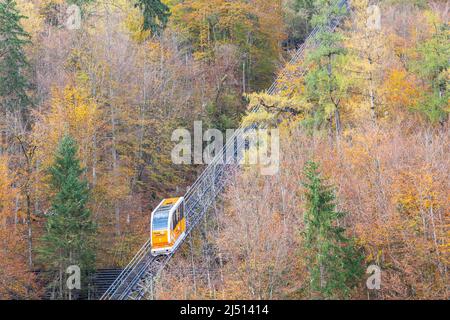 Hallstatt, Autriche - 2 novembre 2019 : le wagon orange monte sur la pente pour servir les touristes du sol au sommet de Hallstatt. Arbres changeant Banque D'Images