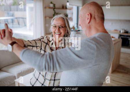 Couple senior joyeux dansant ensemble à la maison. Banque D'Images