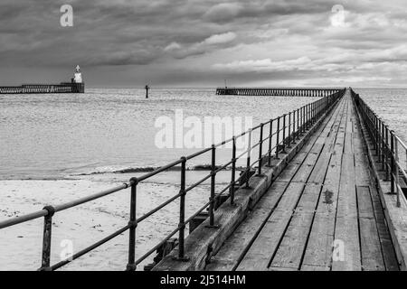 Les deux vieilles jetées en bois protégeant l'entrée du port de Blyth dans Northumberland, avec le joli phare sur la jetée nord au loin. Banque D'Images