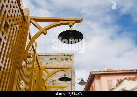 Lampe, une lampe de rue esthétique attachée au fer forgé jaune, conception et éclairage minimaux, électricité et lumière Banque D'Images