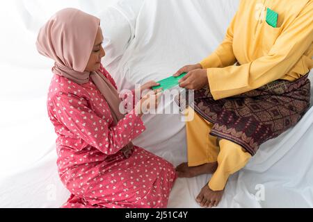 Le couple musulman célèbre la fin du Ramadan, le mois Saint islamique, donne un cadeau de paquet d'argent, cherchant le pardon, canapé blanc, fond blanc Banque D'Images