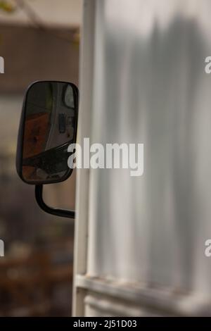 le reflet dans le rétroviseur extérieur vous permet de voir l'intérieur de la cabine avec le siège conducteur et le volant noir. Banque D'Images