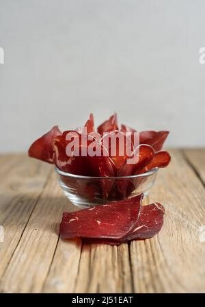 Tranches de bresaola de viande saccadées dans le bawl de verre sur la table en bois avec espace de copie Banque D'Images