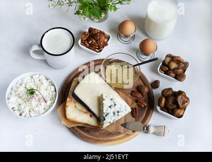 Assiette de fromages avec sauce à la poire, pot à lait, kéfir, fromage cottage, noix sur fond clair Banque D'Images