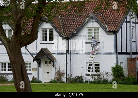 Jeune homme peint maison à colombages dans le village d'Askham Richard, North Yorkshire, Angleterre Banque D'Images