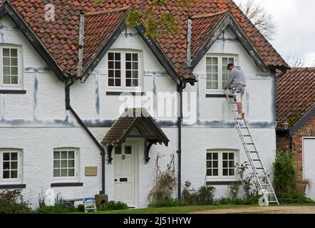 Jeune homme peint maison à colombages dans le village d'Askham Richard, North Yorkshire, Angleterre Banque D'Images