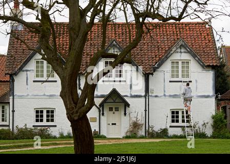 Jeune homme peint maison à colombages dans le village d'Askham Richard, North Yorkshire, Angleterre Banque D'Images