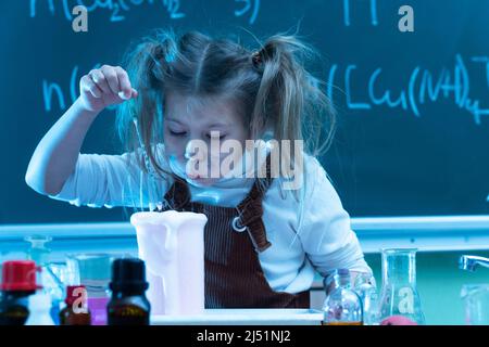 Mignonne petite fille mélange des produits chimiques pendant la leçon de chimie à l'école Banque D'Images