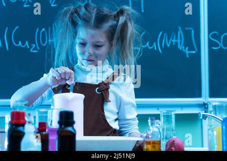 Mignonne petite fille mélange des produits chimiques pendant la leçon de chimie à l'école Banque D'Images